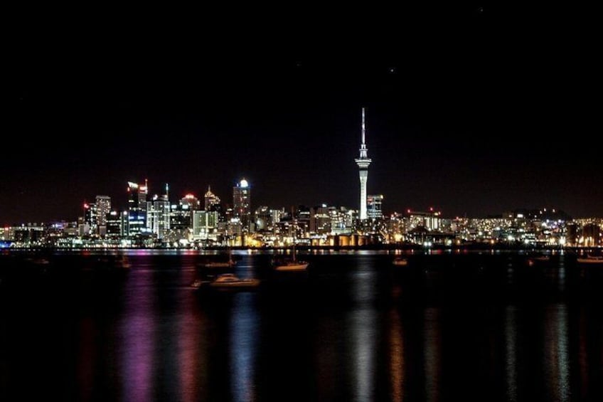 A city skyline at night with a prominent tower and illuminated buildings. 3