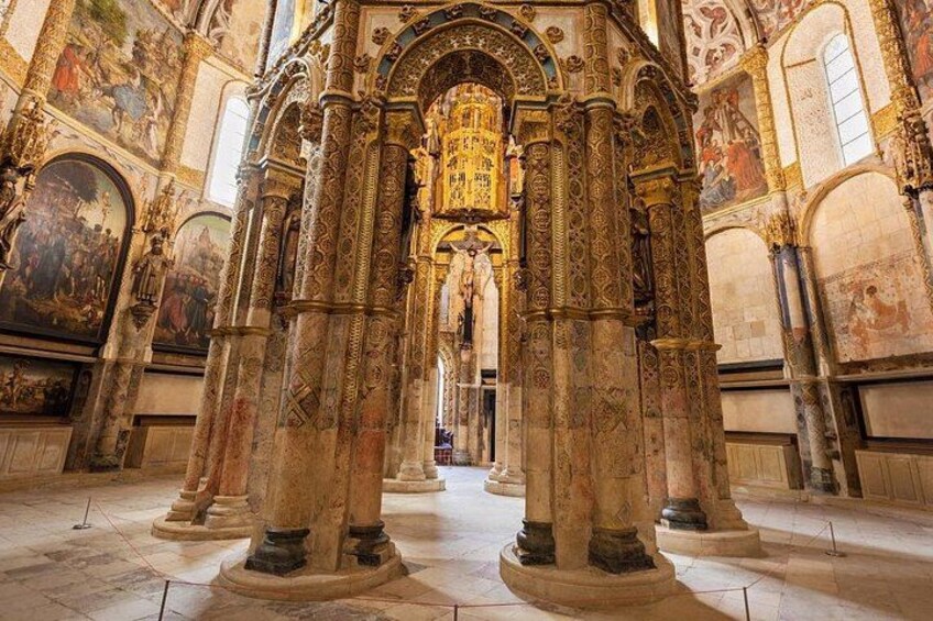 An ornate church interior with detailed columns, a central altar, and religious paintings on the walls. 1