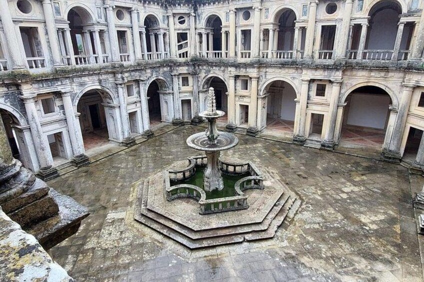 An ancient courtyard with a central fountain, surrounded by arched walkways and columns. 2