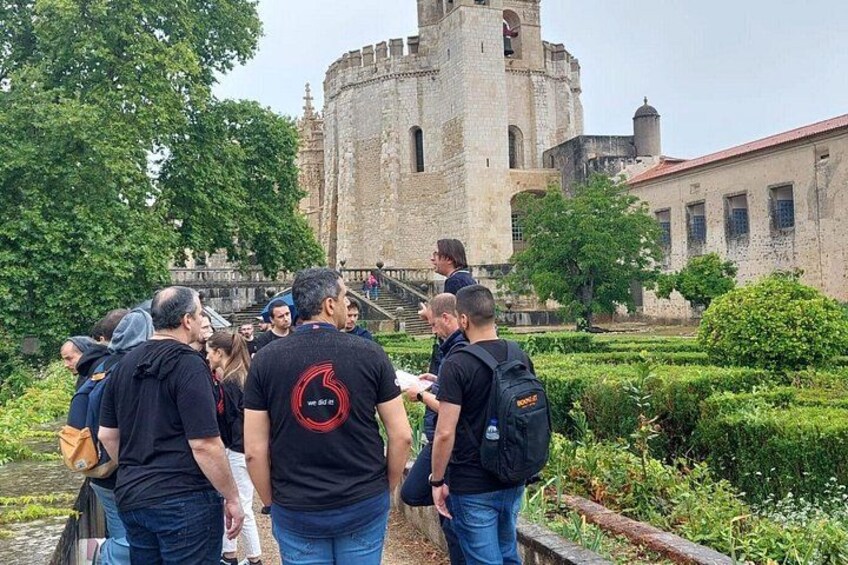 A group of people standing in a garden area with a historic building in the background. 3