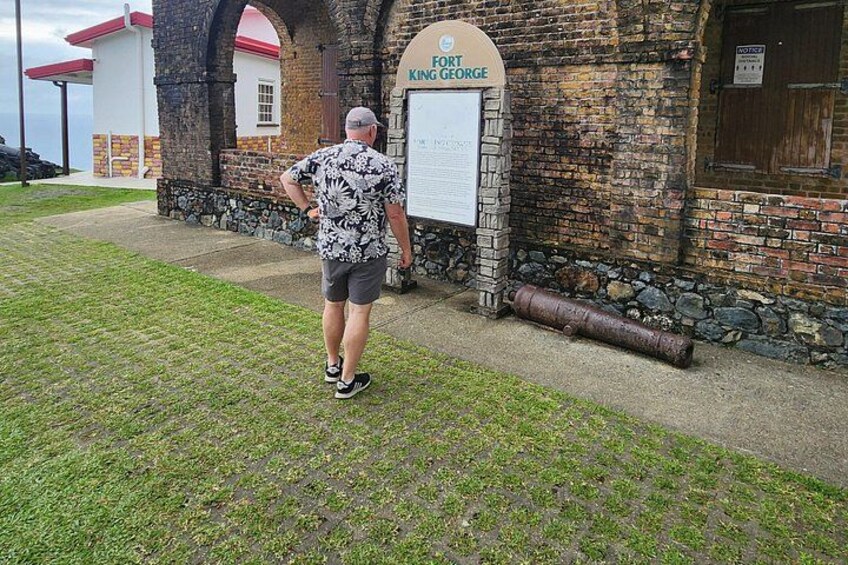 Un hombre caminando frente a un edificio con la leyenda 'Fort King George' y un marcador histórico. 4