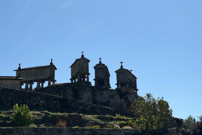 A series of stone structures with crosses on top, situated on a rocky hill under a clear blue sky. 2