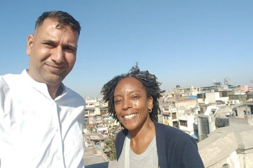 Zwei Personen stehen auf einem Dach mit Stadtansicht im Hintergrund. 4