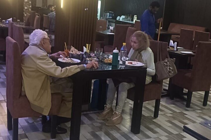 Drei Personen sitzen an einem Tisch in einem Restaurant mit Stühlen und einem Fliesenboden. 5