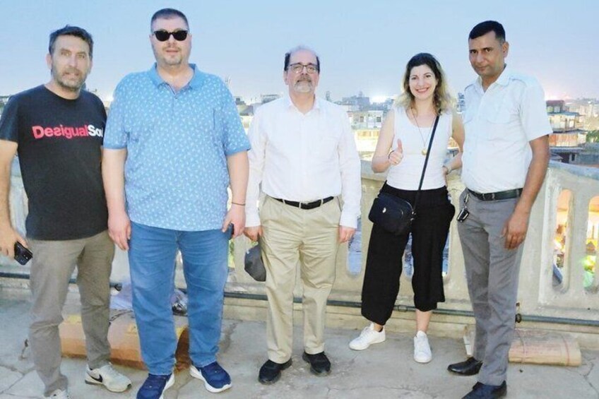 Eine Gruppe von fünf Personen steht auf einer Brücke mit einer Stadtansicht im Hintergrund. 3