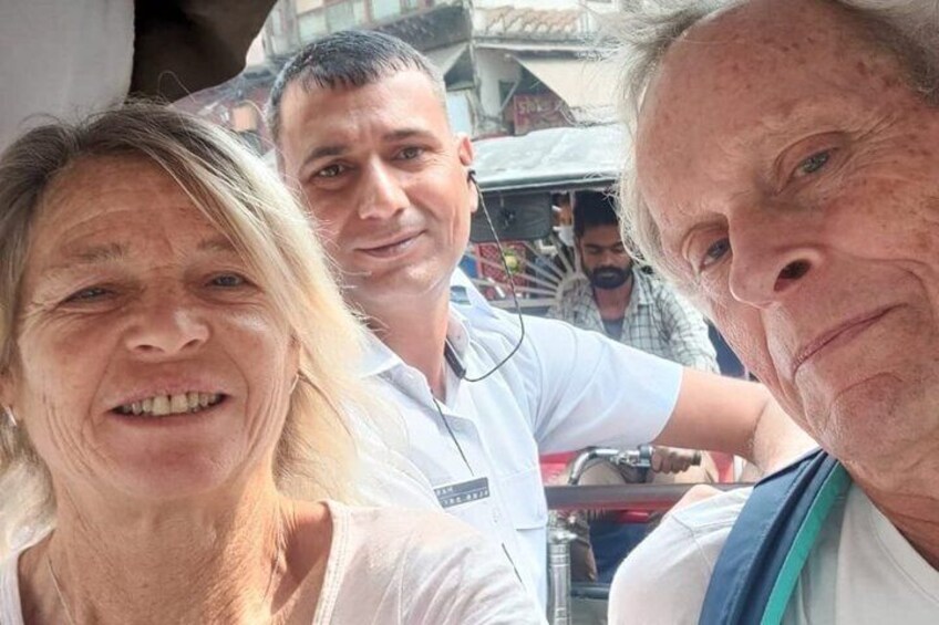 Drei Personen stehen draußen, im Hintergrund ein Marktstand und ein Fahrzeug. 2