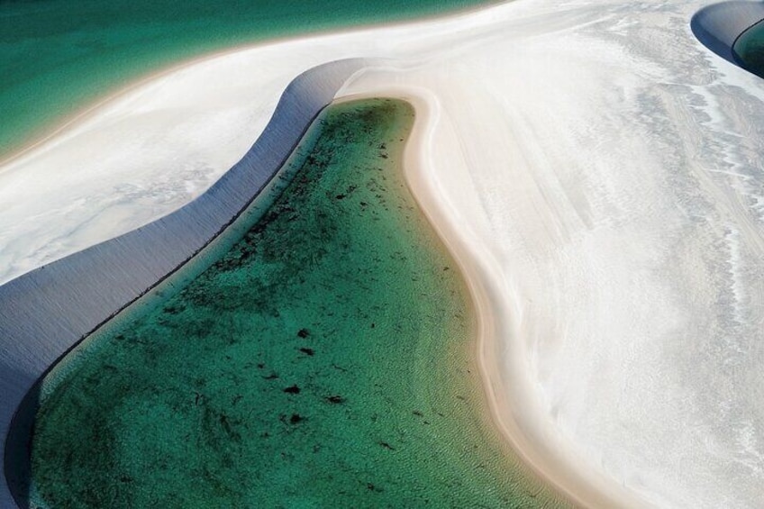 En vy över en strand, tagen från luften, med kristallklart turkosfärgat vatten och vit sand. 2