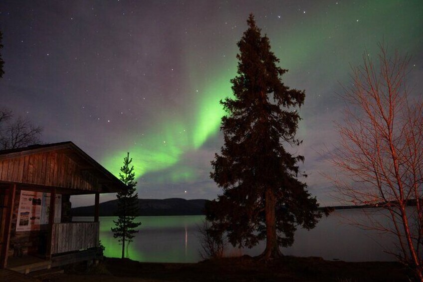 A wooden cabin by a lake with the Northern Lights in the sky. 3