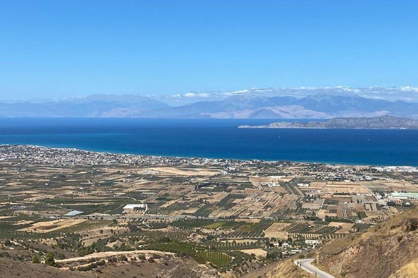 A coastal landscape with a town, agricultural fields, and distant mountains. 3
