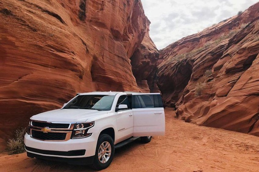 A white SUV parked in a red rock canyon. 2