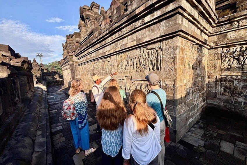 Tourists observing ancient stone carvings at a historical site. 2