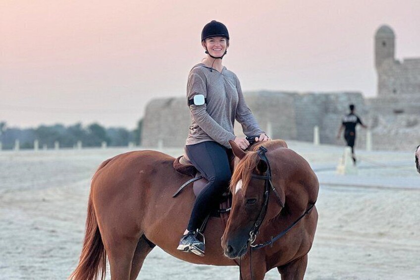 A person riding a horse on a beach with a castle in the background. 2