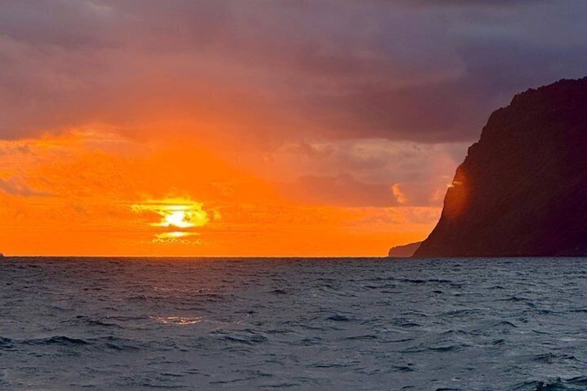 Ein Sonnenuntergang über dem Meer mit einer Klippe im Hintergrund. 4