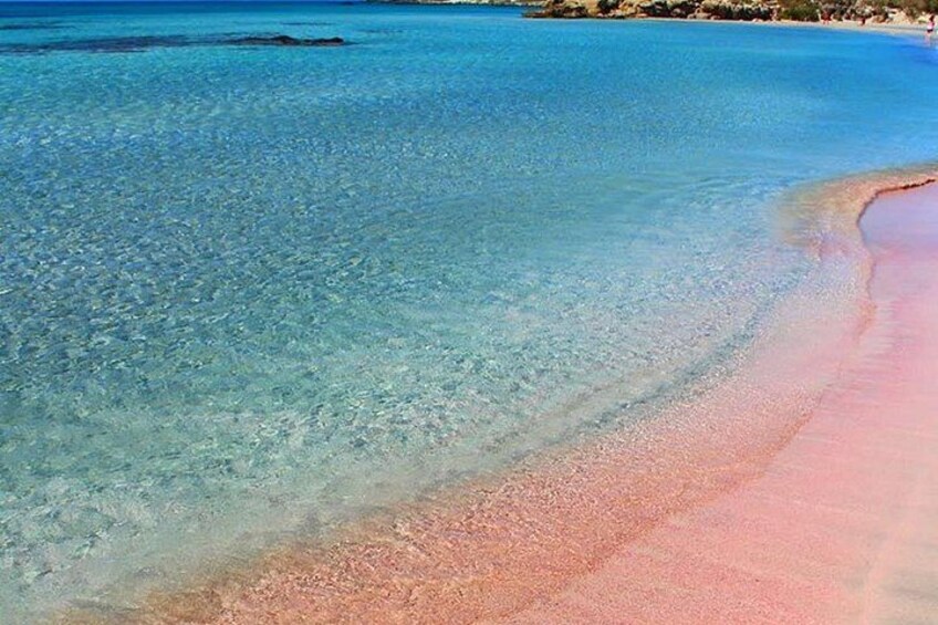 En strand med klart, grunt vatten och en rosa sandstrand. 3
