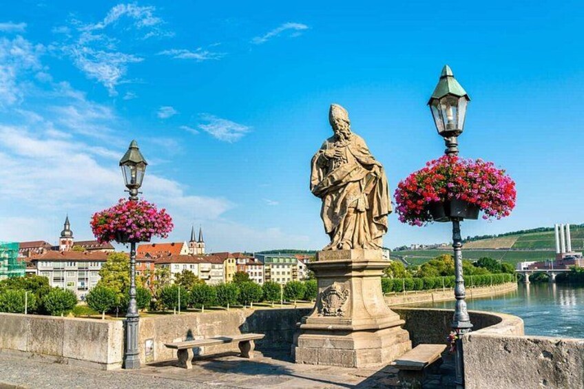 A statue, a bench, a lamppost with flowers, and a river. 3