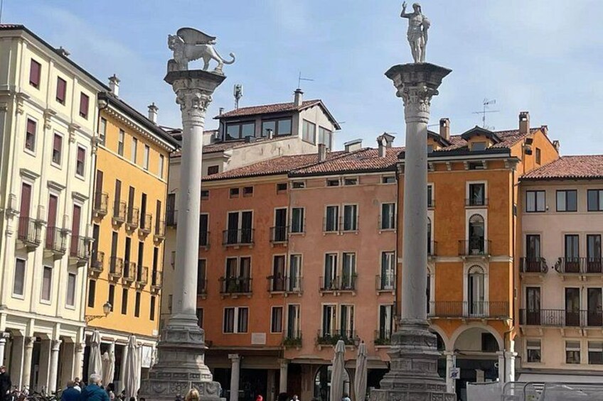 A historic square with ornate columns and classical statues, surrounded by colorful buildings with balconies. 5