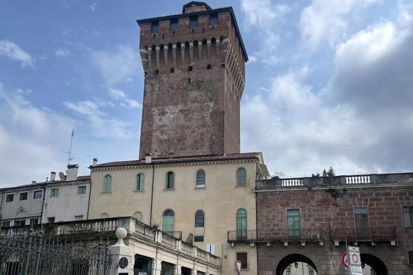 A historic tower with a clock, a building with arched windows, and a wrought iron gate. 3