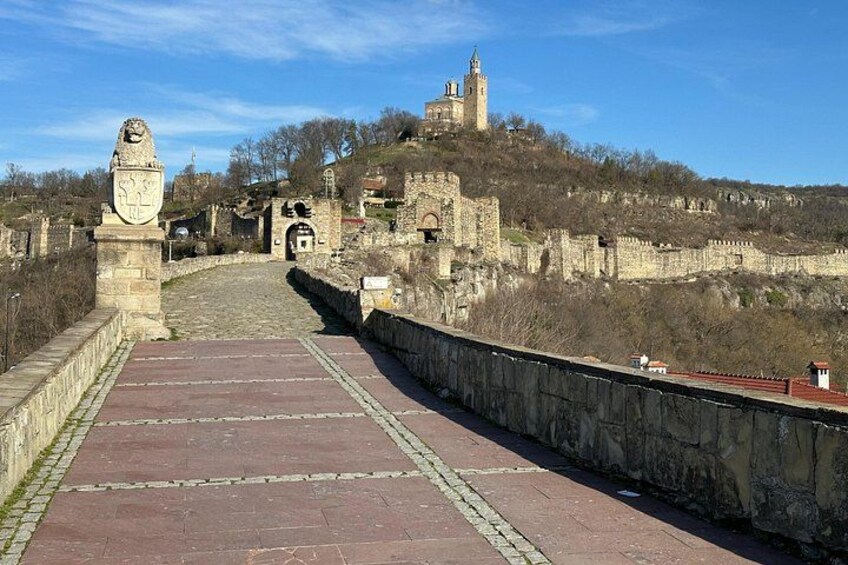 A stone bridge leading to a historic castle on a hill. 2