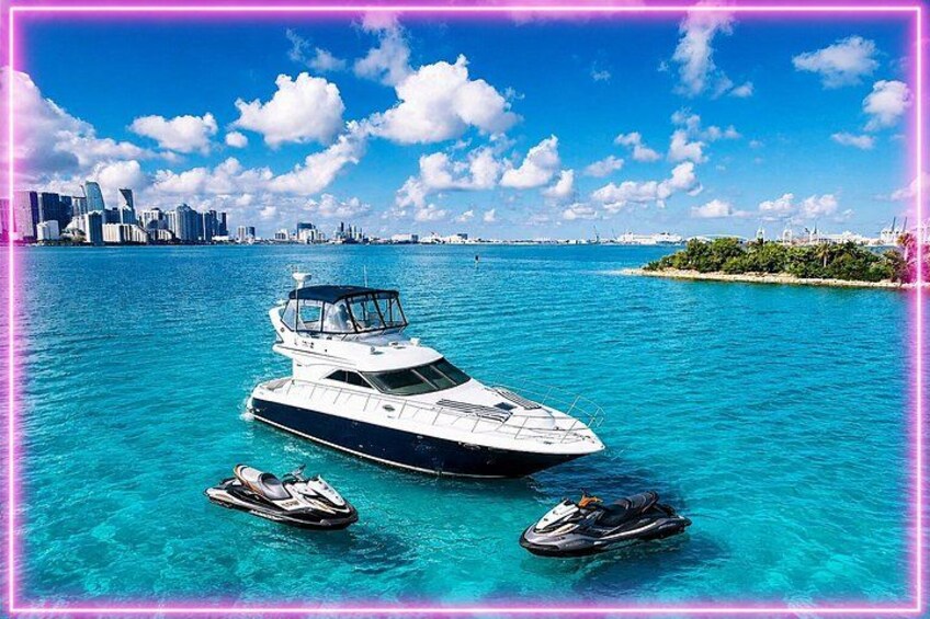 A yacht on clear turquoise water with a city skyline in the background. 1