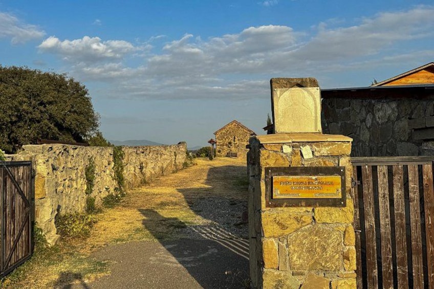 Eine Steinsäule, ein hölzernes Tor und ein Gebäude in der Ferne. 2