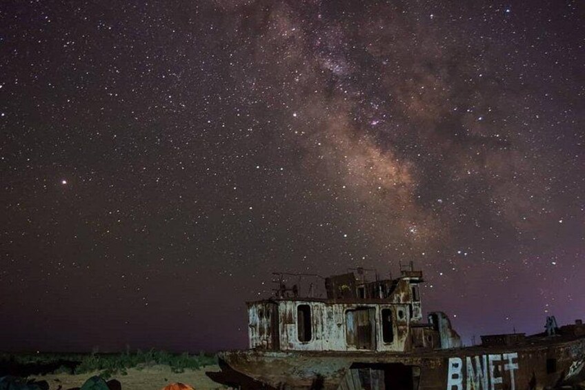 A starry night sky with the Milky Way visible, a dilapidated building, and the text 'BAWET' on the structure. 4