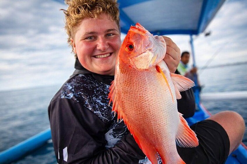 A person holding a fish on a boat. 1
