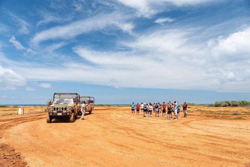A group of people standing on a dirt road with a vehicle parked nearby. 3