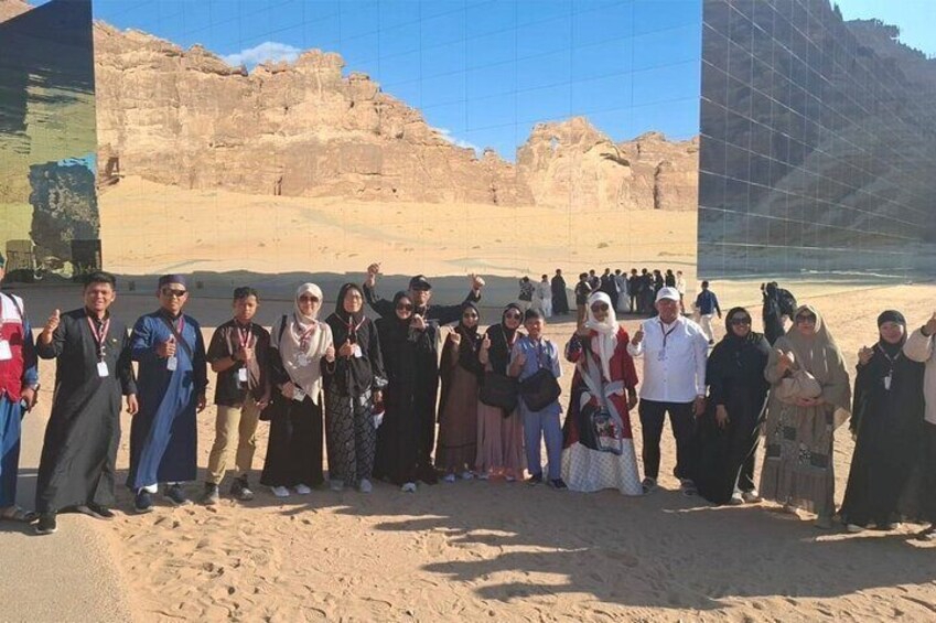 A group of people standing in a desert with ancient rock formations in the background. 1