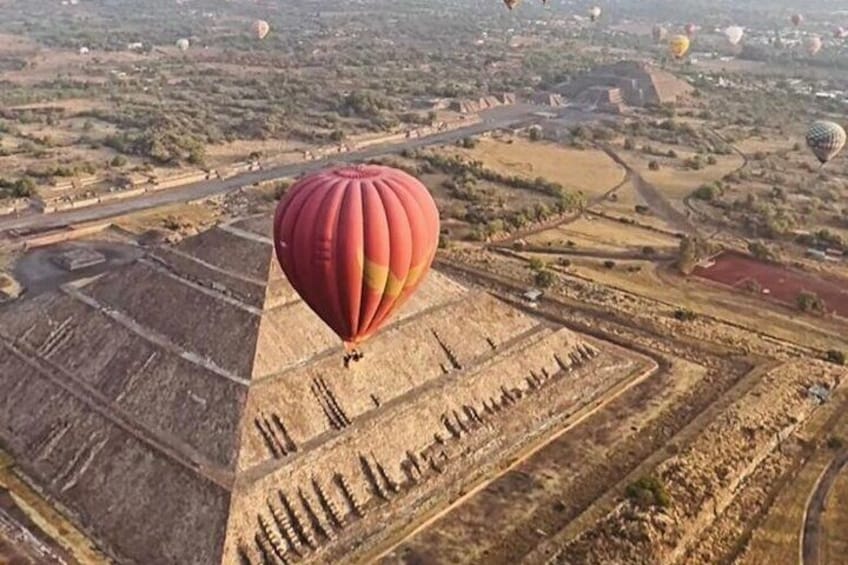 A hot air balloon flying over a landscape with fields and roads. 1