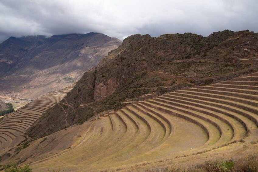 Terraced fields on a hillside, a mountain range in the background, and a cloudy sky. 3