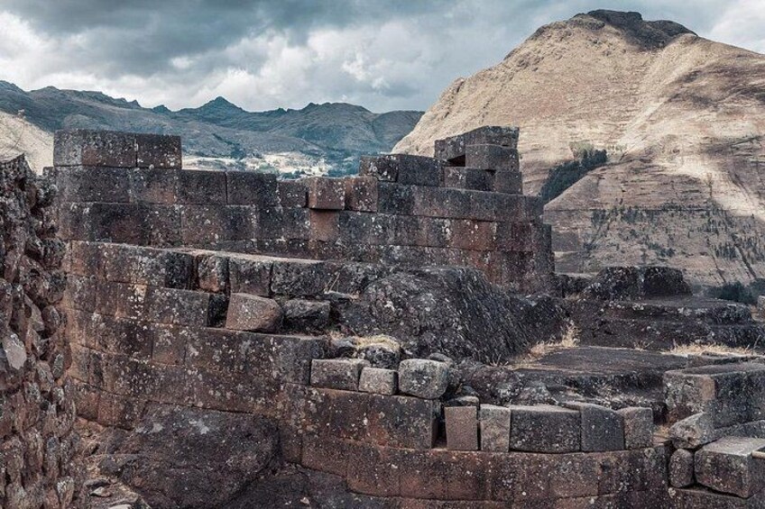 Ancient stone walls and ruins, with mountains in the background. 5