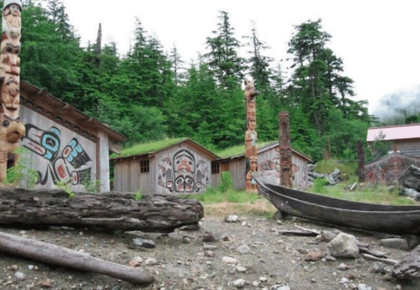 A forested area with traditional totem poles and wooden structures. 2