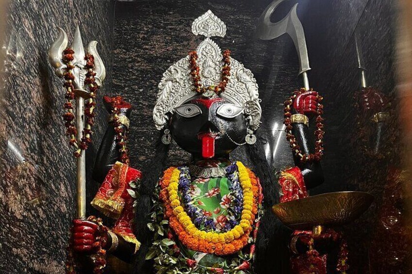 A statue of a deity with multiple arms, adorned with garlands and holding a trident. 3