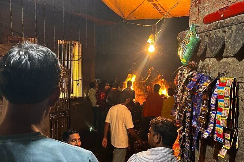 A crowded indoor setting with people gathered around a central fire, possibly for a ritual or ceremony. 2