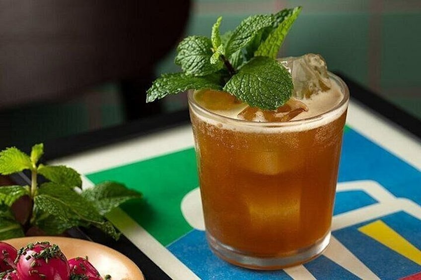 A glass of iced tea with mint leaves on a colorful table. 2