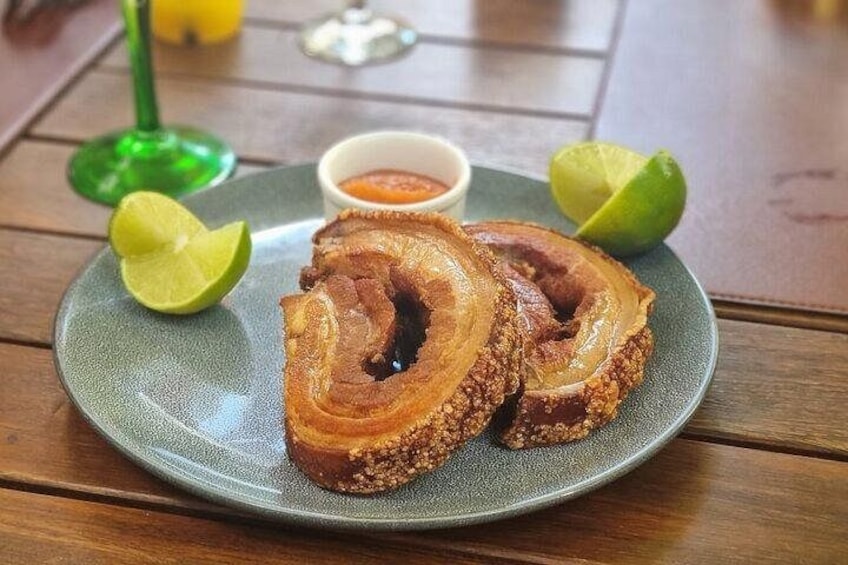 A plate with fried plantains, a lime half, and a small bowl of sauce. 4