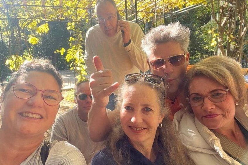 A group of people outdoors with trees and a structure in the background. 5