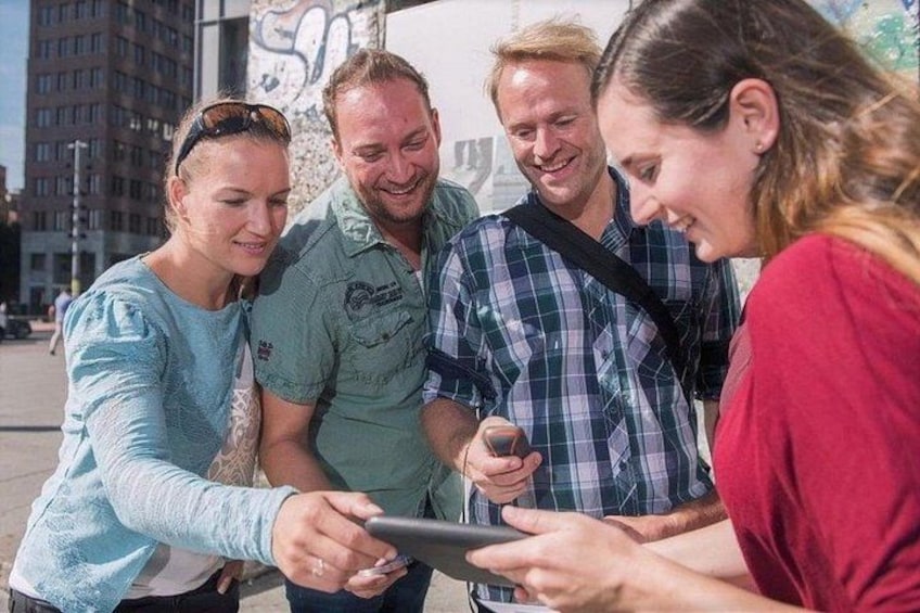 A group of people gathered around a tablet, possibly discussing or viewing something on it. 4