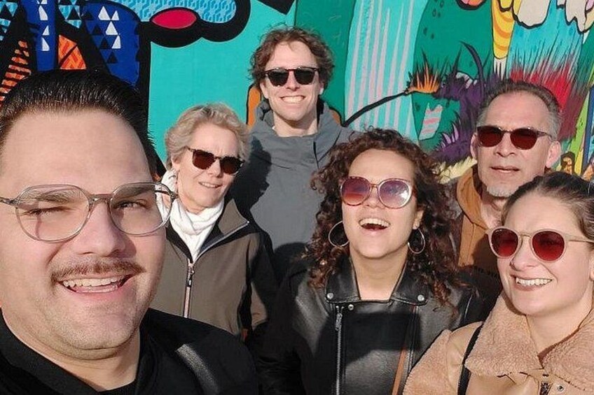 A group of people in front of a colorful mural. 3