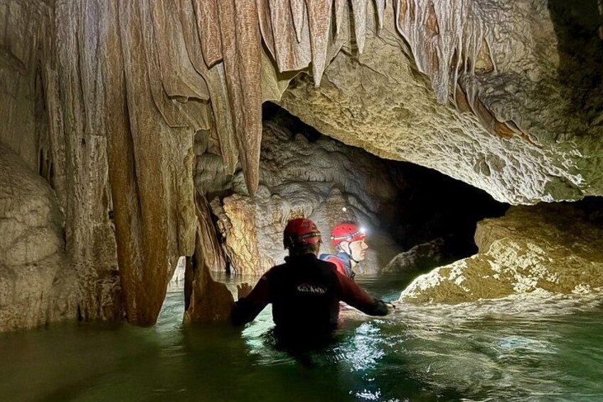 A person wading through a cave with stalactites. 3