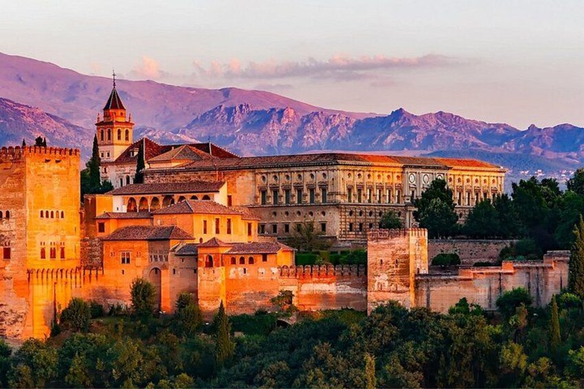 A historic building complex with a prominent tower, surrounded by mountains. 2