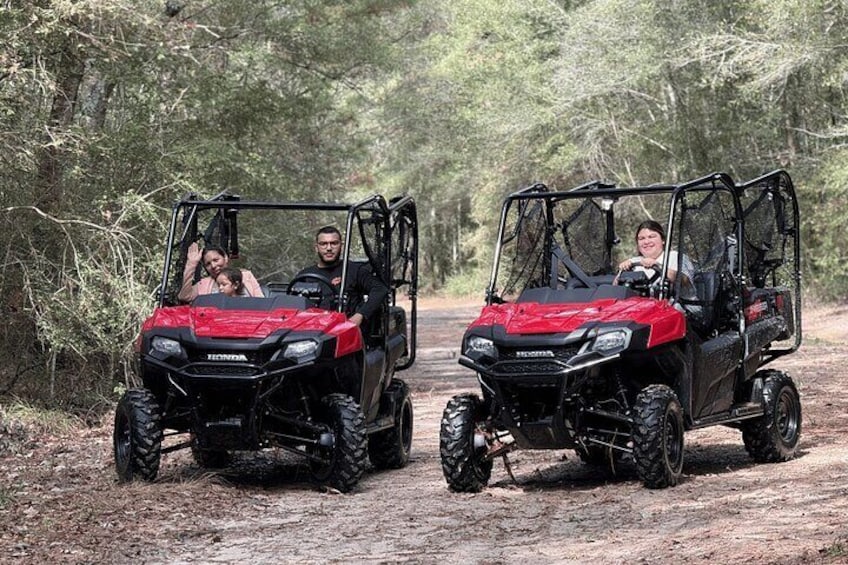 Two off-road vehicles on a dirt path in a wooded area. 1