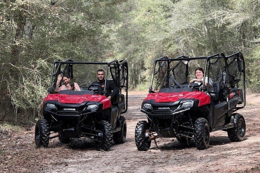 Two red ATVs on a dirt path surrounded by trees. 3