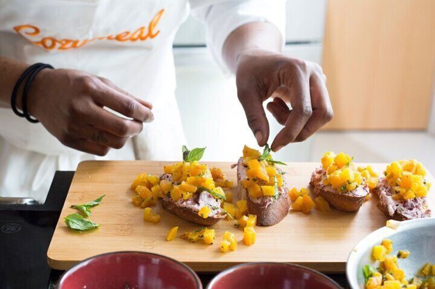 A person preparing food with diced mango on toast. 1