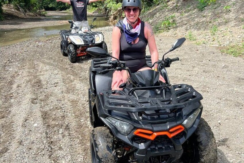 Eine Person fährt mit einem schwarzen ATV auf einem Feldweg, im Hintergrund fließt ein Fluss. 2