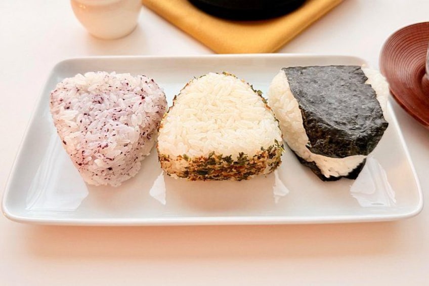 Ein Teller mit drei Sushi-Sorten: eine mit rosa Reis, eine mit weißem Reis und eine mit Seetang. 2