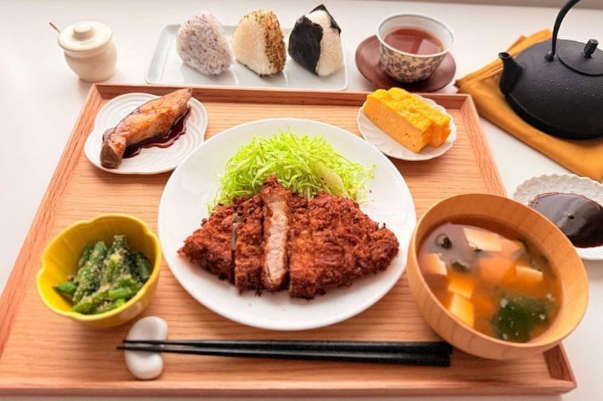 En traditionell japansk måltid med ris, fisk och grönsaker serverad på ett träbricka. 4