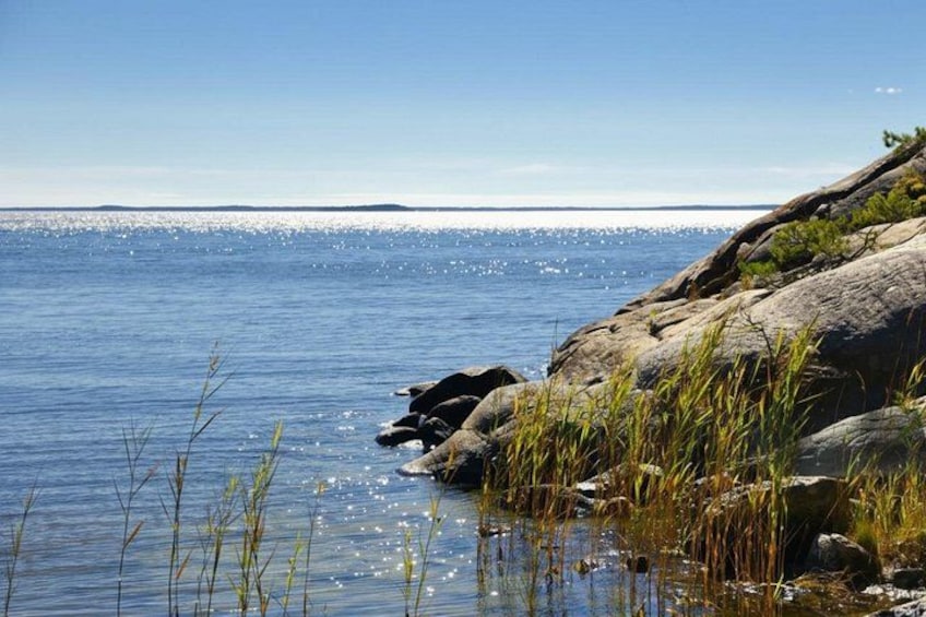 A calm lake with clear blue water, surrounded by rocks and sparse vegetation. 3