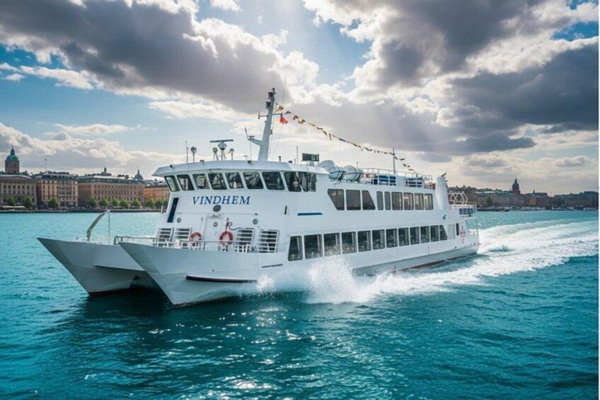 A white cruise ship named VINDHEIM sailing on a body of water with a cityscape in the background. 1