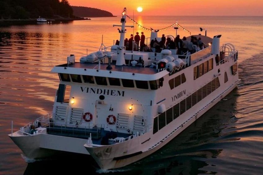 A white boat named VINDHEIM on a body of water during sunset. 2